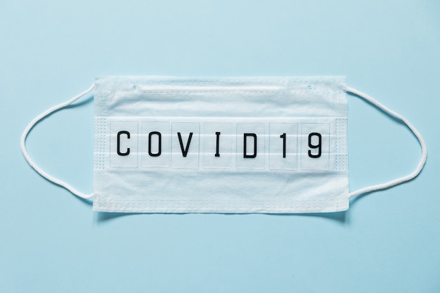 Blue surgical mask with coronavirus text written on it. 2019-nCoV virus infection in Wuhan city. Covid-19 ( SARS-CoV-2 ) spread around the world. Impact of pandemic virus.