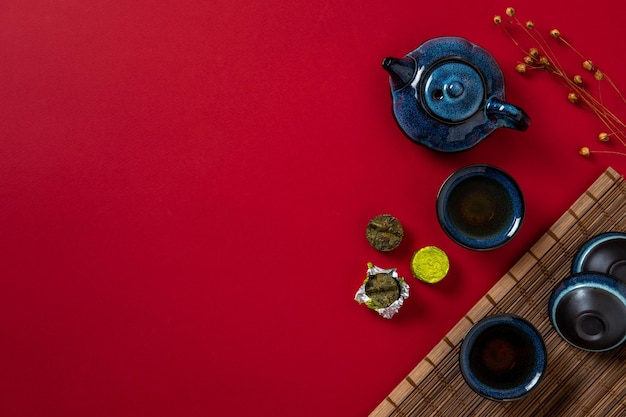 Blue teapot cup of tea and tea leaves on red background Hot herbal tea is in the teapot on the table Copy space