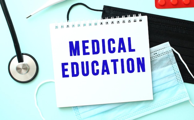 The blue text medical education is written in a notebook that lies on a blue background next to a me