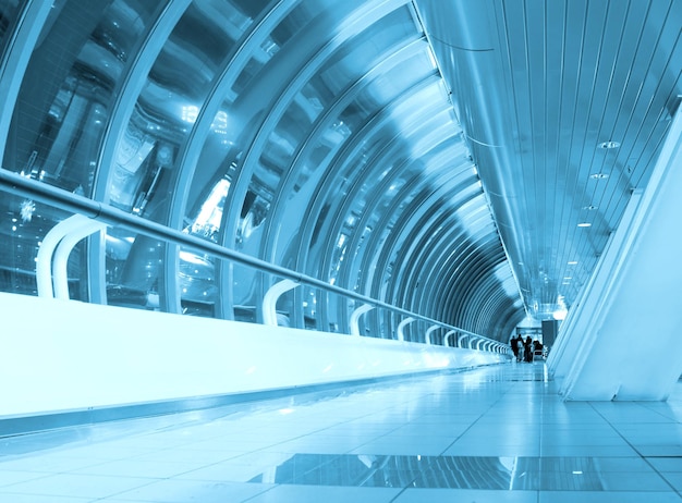 A blue tunnel with people walking down it and the word exit on the right.