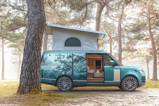 Photo a blue van with a camper on the roof is parked in front of a tree