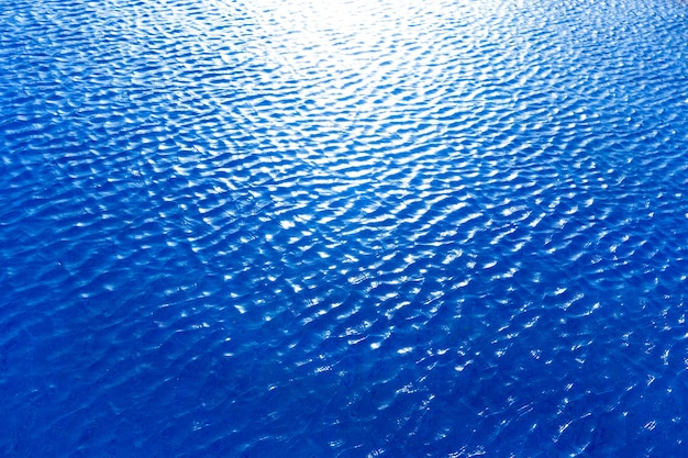 Blue water background with sun reflections