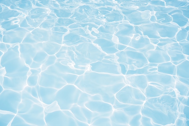 Blue water surface with bright sun light reflections in swimming pool background