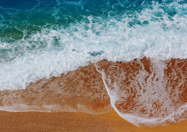 Blue wave on the beach. Blur background and sunlight spots.