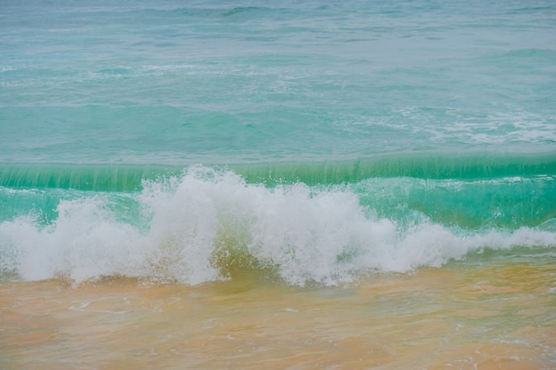 Blue waves of the ocean and yellow sand of the beach.