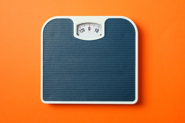 Blue weigh scales on orange background, top view