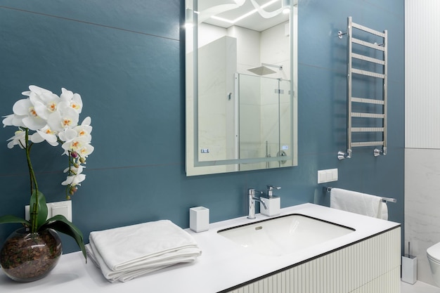 Blue and white bathroom with big mirror towels lighting and countertop basin