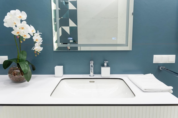 Blue and white bathroom with big mirror towels lighting and countertop basin