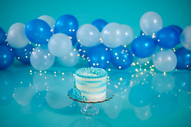 Blue and white birthday cake with balloons in the background. Photo set decoration for photo shoot.