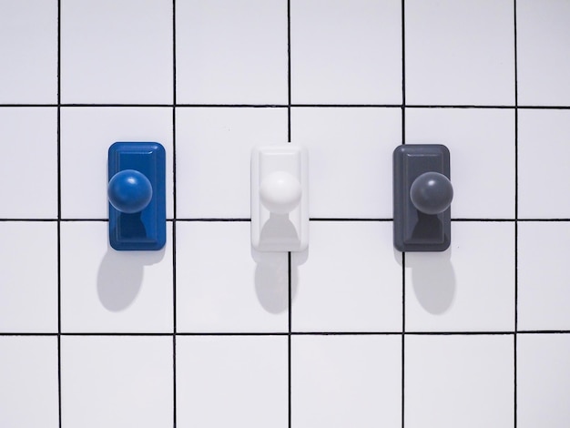 Blue white black color wall mount hooks hanging on white tile wall