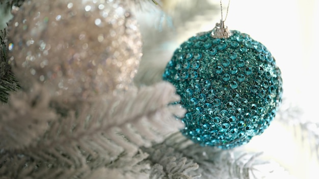 Blue and white christmas balls hanging on snow covered spruce branch closeup