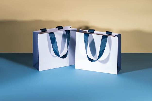 Photo blue and white paper shopping bags mockup with blue handles