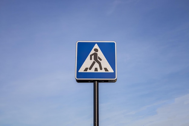 Blue and white pedestrian crossing sign on the sky background