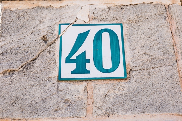 Blue white vintage house number forty 40 on a old aged wall