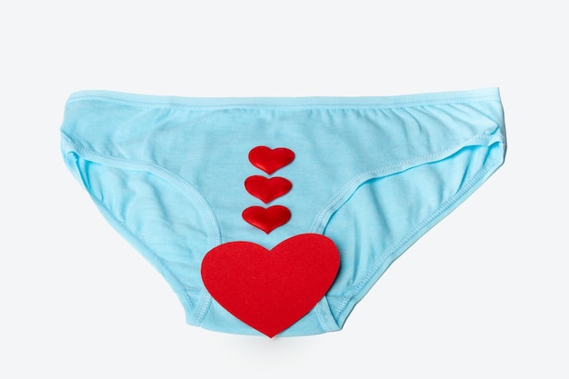 Blue women's panties and red hearts as a symbol of women's health on a white background Women's health concept