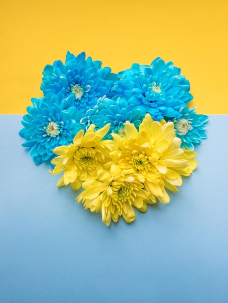 Blue and yellow background with blue and yellow floral heart on it. Stand with Ukraine