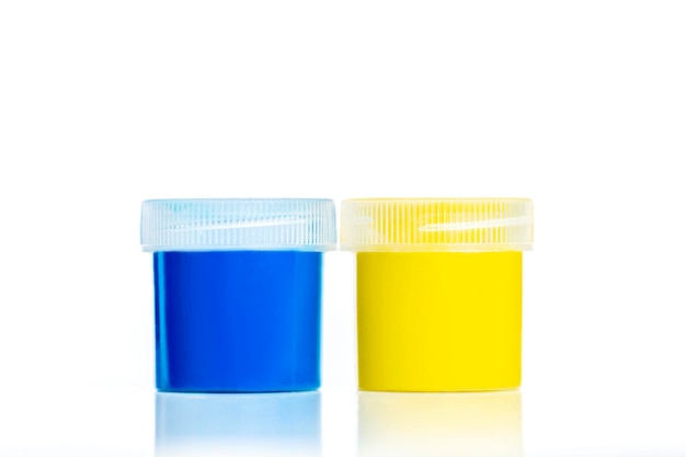 Blue and yellow jars with gouache Hobbies and creativity Closeup Isolated on white background with reflection