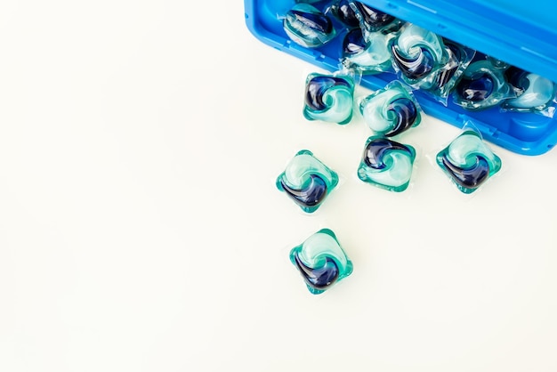 Blueandblue washing capsules are scattered on a white background The process of washing clothes Liquid washing gel