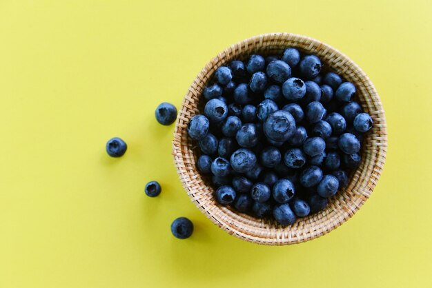 Blueberries in basket on yellow background 