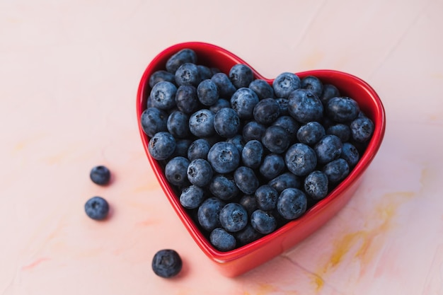 Blueberries in bowl on pink background copy space