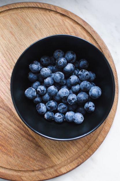 Blueberries in bowl on wooden plate