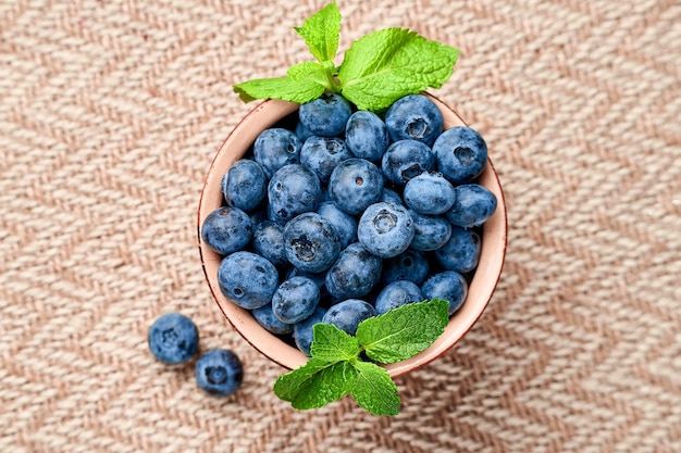 blueberries in a ceramic bowl on a beige cloth View from above