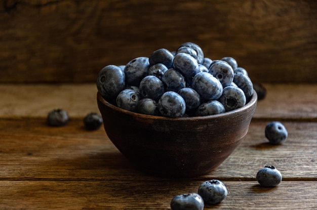 Blueberries in a clay cup, on a wooden table. Ripe berries in the kitchen, harvest.