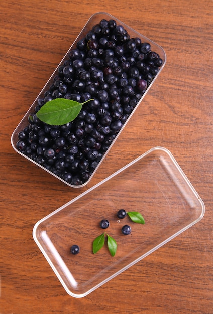 Photo blueberries, currant with leaf in box on wooden space