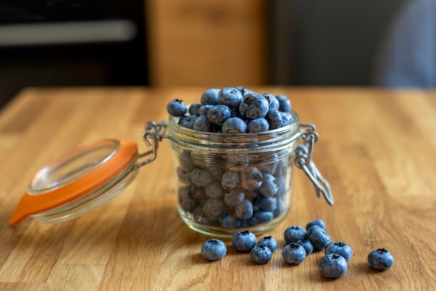 Blueberries in glass jar on a wooden background