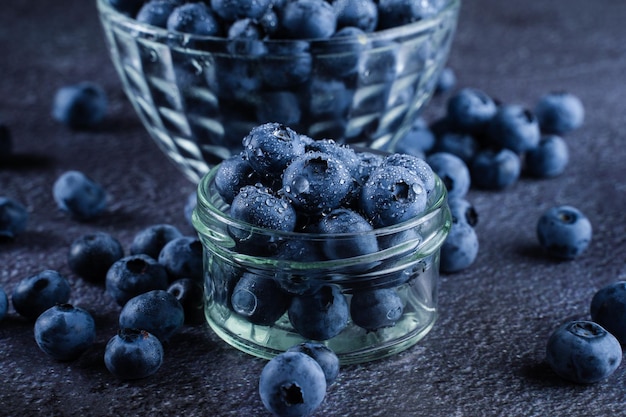 Blueberries organic natural berry with water drops on dark background closeup Blueberry in glass bowl plate