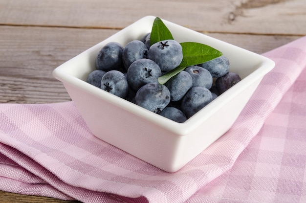 Blueberries in a porcelain dish on wooden background