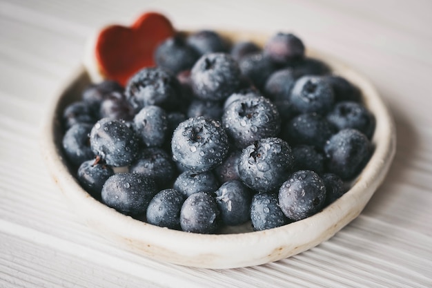 Blueberries in a small ceramic bowl with a red heart decor closeup