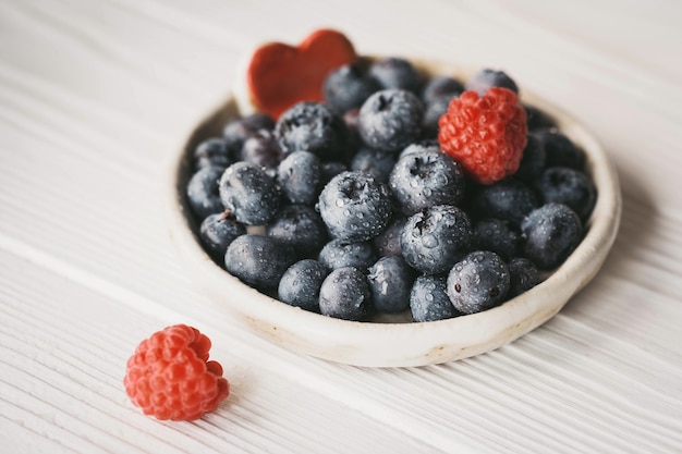 Blueberries in a small ceramic bowl with a red heart decor closeup