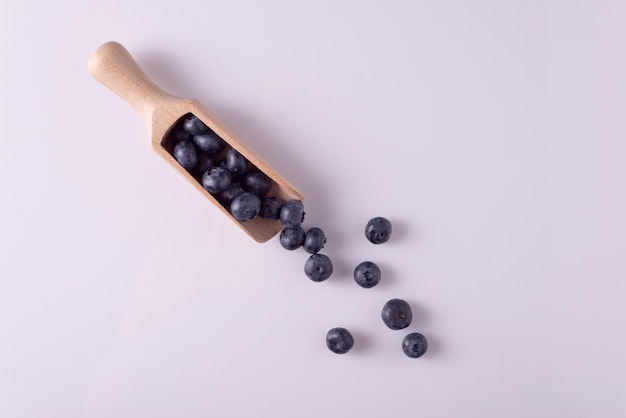 Blueberries in a wooden spoon on a white table