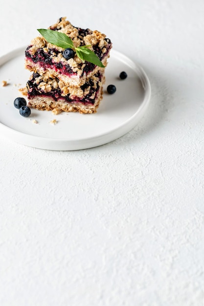 Blueberry crumble bars on a plate with mint on white background Healthy snack for school Text space