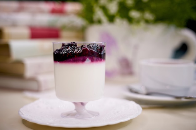 Blueberry dessert with tea on the table with flowers and books.