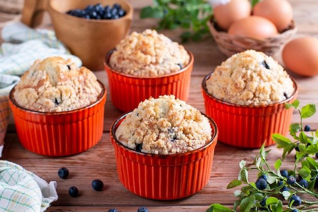 Blueberry muffins baked with fresh blueberries on wooden table with fresh mint