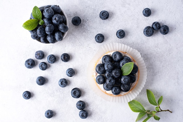 Blueberry tart and ripe berries in a bowl on a white background.