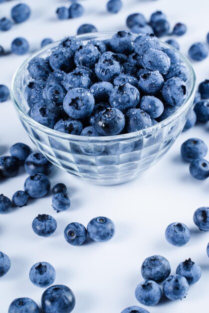 Blueberry with water drops Blue berries in glass plate on white background Many natural organic blueberries Vertical photo