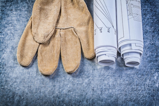 Blueprints safety gloves on metallic background construction concept