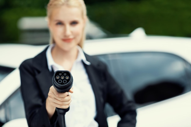 Blur closeup progressive woman holding and point EV plug for electric vehicle