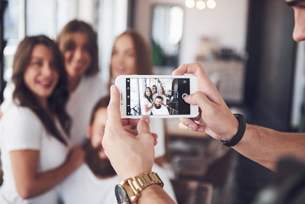 Blur portrait of blissful young best friends with hands holding phone on foreground.