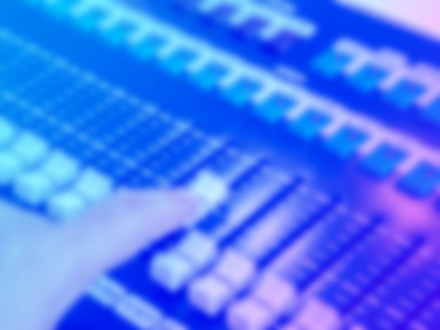 Blurred abstract background of hand that tuning on mixer for music mixing on blue pink color tones Defocused of mixer buttons in recording sound studio or concert control panel