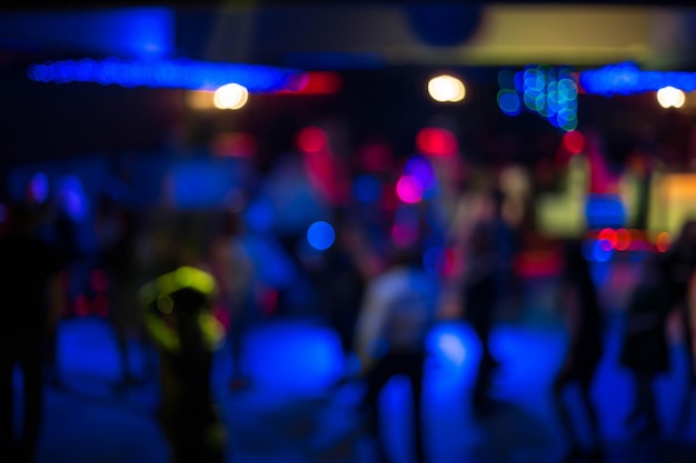 Blurred abstract image of people dancing in a nightclub. Men and women dancing in a nightclub on a dark background