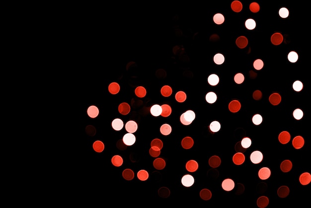 Blurred abstract sparkling lights background with heart shape on black backdrop.