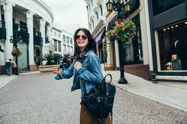 blurred background Redeo Drive at Beverly Hills asian girl striding the pavement is looking back and smiling radiantly to her boyfriend. follow me concept