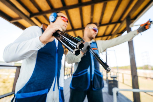 Blurred background of two adult mans in sunglasses protective headphones and a rifle vest