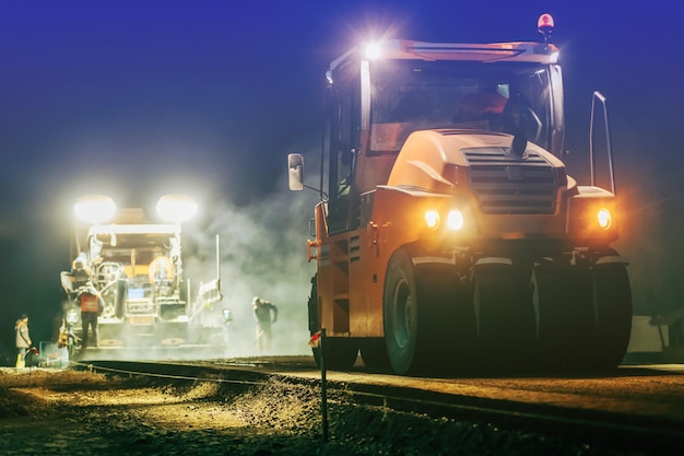 Blurred background of of vibratory asphalt rollers compactor compacting new asphalt pavement at nigh