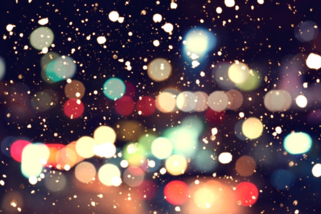 Blurred bokeh background of colorful christmas lights with snow fall from christmas night party.