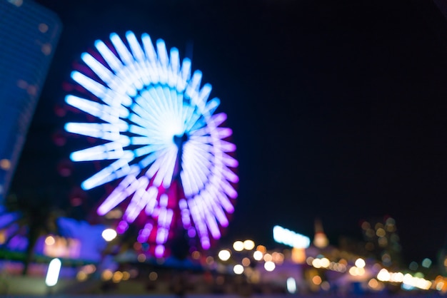 Blurred bokeh night harbor lights background with ferris wheel